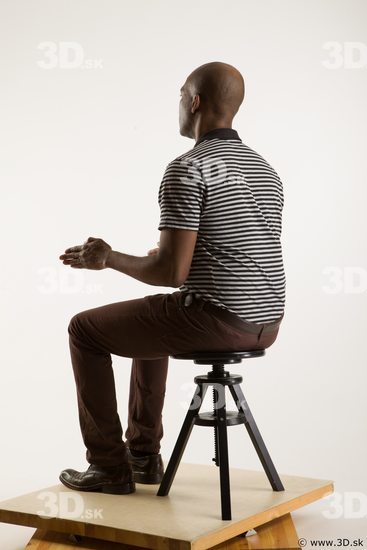 Sitting reference of whole body black white striped shirt brown jeans brown shoes Arturo